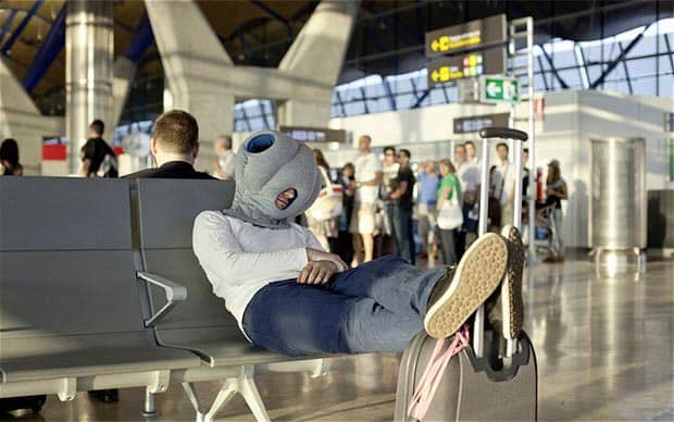 A Man Having A Power Nap At The Airport Lounge With Ostrich Pillow