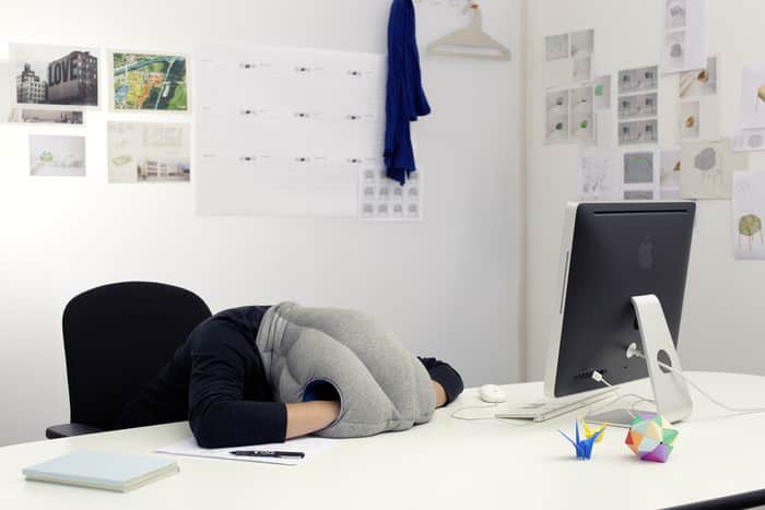 A Person Having A Power Nap In Office With Ostrich Pillow