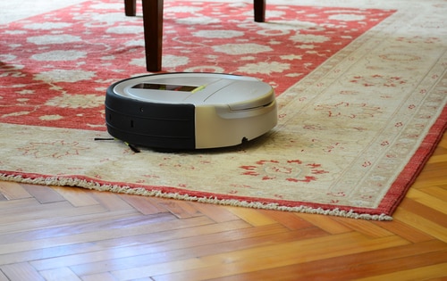 Automatic cleaning with robot vacuum cleaner on rug and hardwood floor